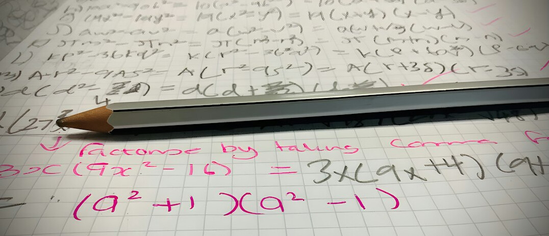 Notebook with handwritten pseudocode next to a laptop